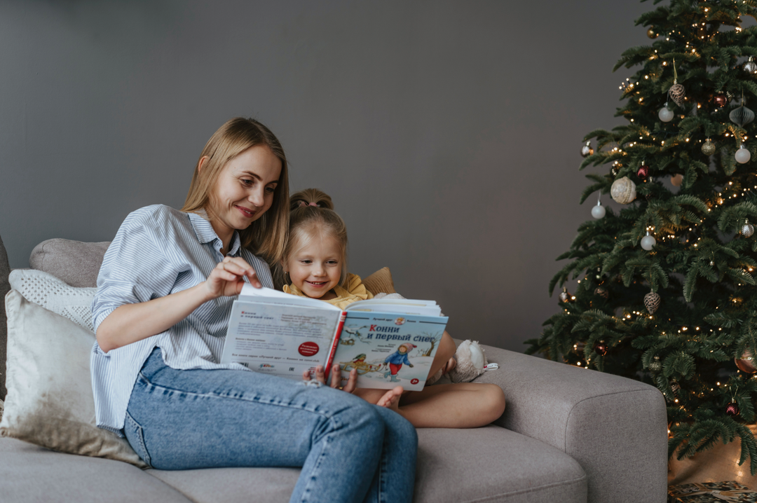 madre e hija sentadas en el sofa mientras leen un libro
