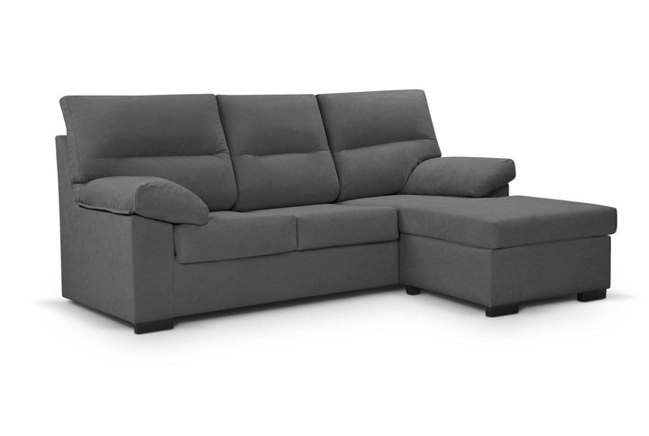 Un moderno sofá modular gris con mullidos cojines y una chaise longue a la derecha. La tela es suave, lo que crea un ambiente acogedor y agradable.