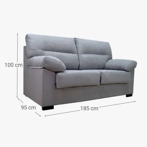 Sofá gris de dos plazas con cojines mullidos, mostrado sobre un fondo blanco. Las dimensiones del sofá son 185 cm de ancho, 95 cm de profundidad y 100 cm de altura.