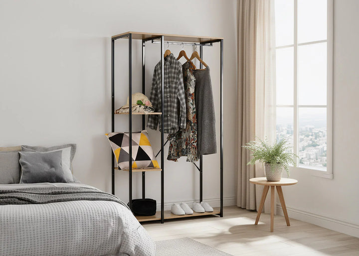 Dormitorio minimalista con la cama perfectamente hecha, un armario abierto con ropa, cojines geométricos y una planta en una maceta sobre una mesita junto a un gran ventanal.