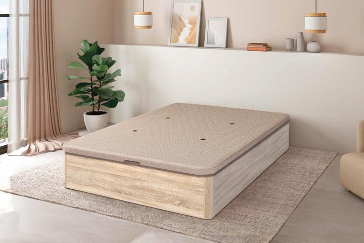 Dormitorio moderno con un diseño minimalista en tonos beige. La habitación cuenta con una cama con plataforma de madera clara sobre una alfombra con textura, una planta en maceta y una suave iluminación colgante.