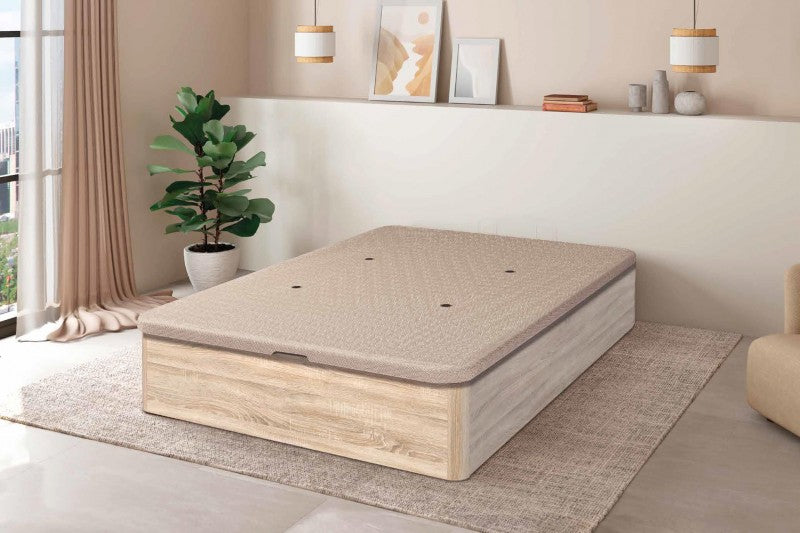 Dormitorio moderno con un diseño minimalista en tonos beige. La habitación cuenta con una cama con plataforma de madera clara sobre una alfombra con textura, una planta en maceta y una suave iluminación colgante.