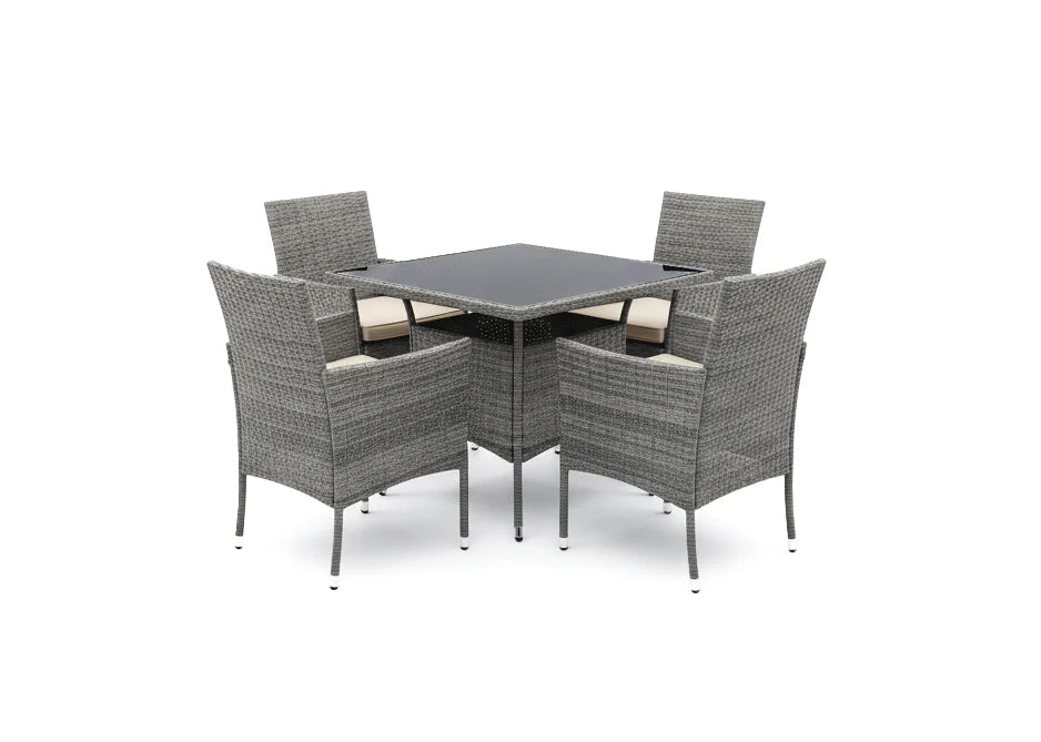 Mesa cuadrada con tablero de cristal y cuatro sillas de mimbre gris. Las sillas tienen cojines claros, lo que crea un ambiente moderno y acogedor para comer al aire libre.