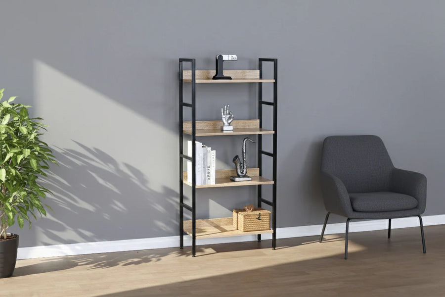 Habitación moderna con un sillón gris, una estantería de metal negro y madera en la que se exponen una escultura de una mano, libros y una caja de mimbre. Una planta en maceta aporta un toque de verdor.