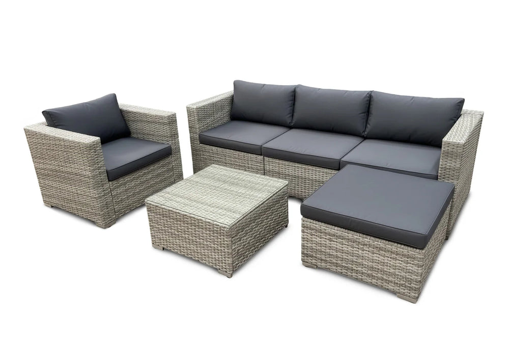 El conjunto de muebles de exterior para terraza incluye un sofá de tres plazas, un sillón, una mesa de centro y una otomana. Los muebles cuentan con cojines grises y estructuras de mimbre.