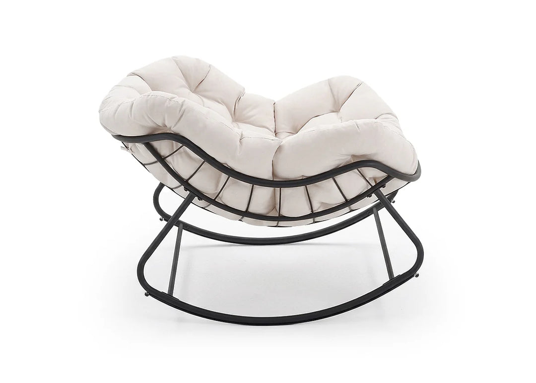 Silla mecedora acolchada en color crema con una elegante estructura de metal negro, que cuenta con un asiento y un respaldo mullidos. Irradia comodidad y elegancia moderna.