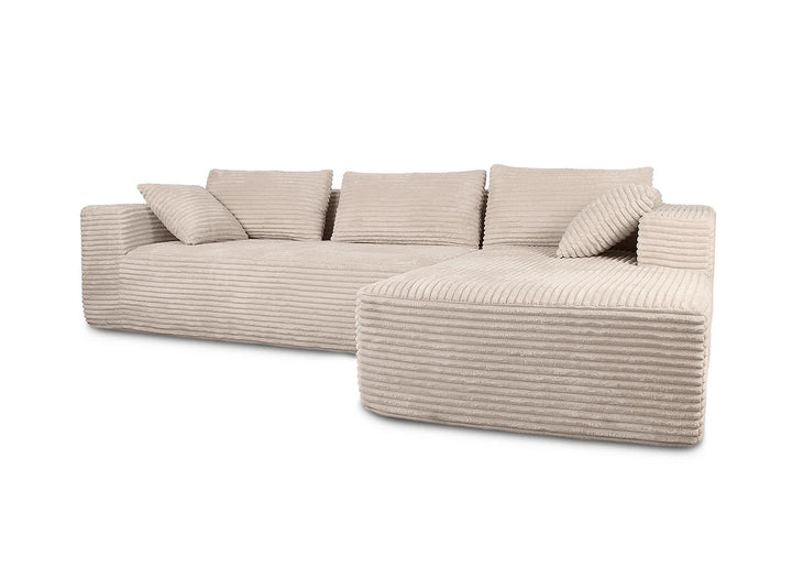 Un moderno sofá modular de pana beige con chaise longue. Cuenta con mullidos cojines y un aspecto acogedor y texturizado, que transmite comodidad y un estilo contemporáneo.