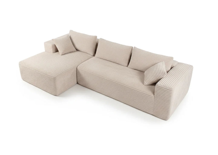Sofá modular de pana en forma de L de color beige, con mullidos cojines y un diseño minimalista y acogedor, que irradia comodidad y elegancia sobre un fondo blanco.