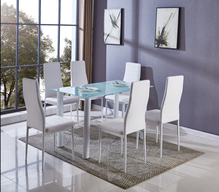 Un comedor moderno cuenta con una mesa de cristal y seis sillas blancas sobre una alfombra beige. La gran ventana y las obras de arte abstracto aportan elegancia y serenidad.